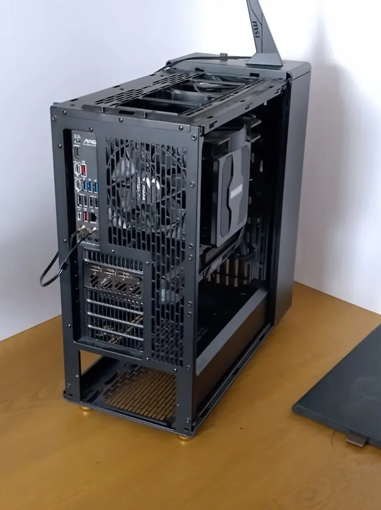 A computer desktop with the top and side panel removed. The angle shows the back of the desktop. There is a gap where the power supply belongs.